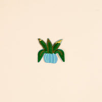 Add a touch of nature to your look with The Darling Effect’s Plant Mix & Match Iron-On Patch—a green potted plant with long leaves in a light blue pot, perfect for personalizing your style.