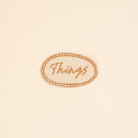 The Darling Effect’s Things Mix & Match Iron-On Patch features “Things” in cursive within an oval border on beige—ideal for customizing jackets or adding to your patch collection.