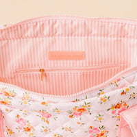 The image shows the open top of the Endless Daydream Cream The Everyday Quilted Tote Bag by the-darling-effect, featuring a pink floral exterior, pink-and-white striped interior, zippered pocket, and a THE DARLING EFFECT label—ideal for daily use.