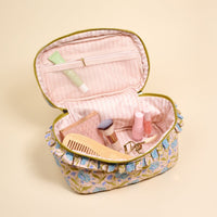 The Darling Effect Poppin' Petals Aqua Glam & Go Quilted Cosmetic Bag opens to reveal a pink lining and holds a makeup brush, comb, eyelash curler, makeup palette, and two nail polish bottles.