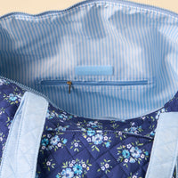 The-darling-effect Endless Daydream Navy On-the-Go Quilted Weekender Bag features a blue floral design, light blue and white striped lining, inner zip pocket, and a branded label. Spacious and perfect for travel.
