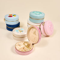 The Darling Effect Bow Pink Round Velvet Jewelry Case features elegant embroidery and multiple accessory compartments, shown open and closed in pastel hues on a beige background, perfect for stylish jewelry storage and organization.