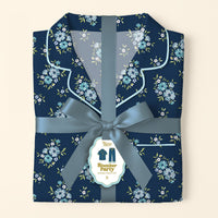 Folded Endless Daydream Navy Slumber Party Pajama Pants Set by The Darling Effect, featuring a light blue and white floral print on ultra-soft fabric, tied with a satin ribbon. Tag displays product name and a relaxed fit illustration.