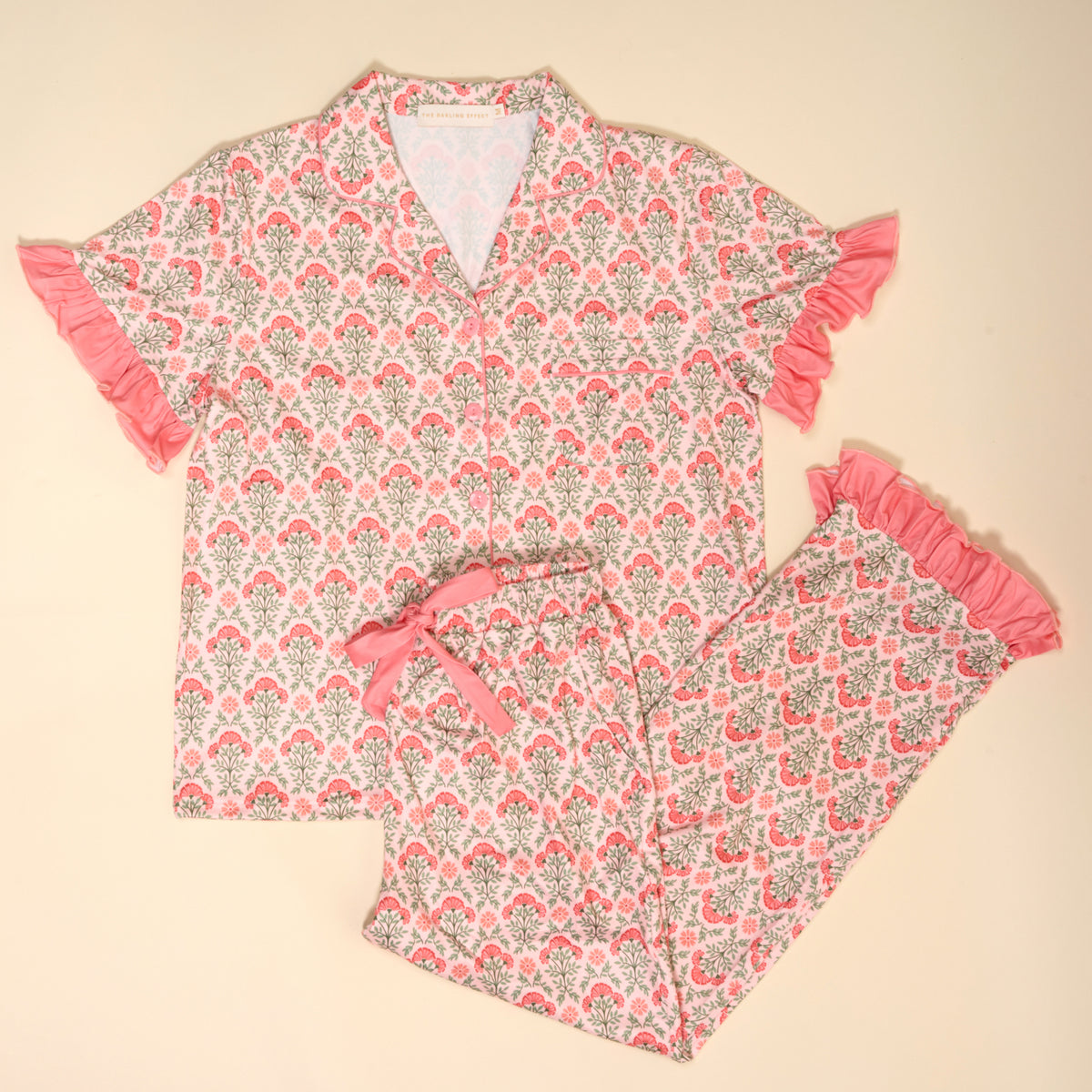 The Darling Effect Everbloom Dusty Rose Slumber Party Pajama Pants Set features a pink and gray floral print, collared button-up top, ruffled trim pants, and ultra-soft fabric, shown laid flat on a light background.