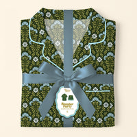 A folded Everbloom Forest Green Slumber Party Pajama Shorts Set by The Darling Effect, featuring a blue and white floral print, is tied with a ribbon. A tag displays an illustration and the set’s name.