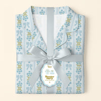 Folded Oh So Fancy Blue Slumber Party Pajama Shorts Set by The Darling Effect features a collared, ultra-soft top and shorts, wrapped in silver satin ribbon with a tag and playful illustrations of the relaxed fit.