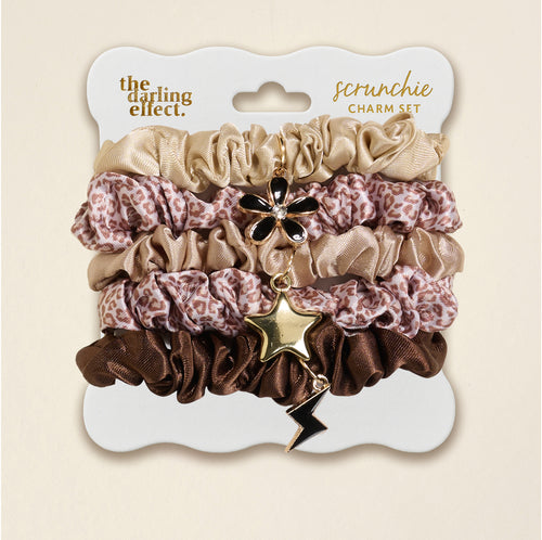 The Darling Effect's Born Wild Scrunchie Charm Set features leopard, gold, and brown scrunchies adorned with flower, star, and lightning bolt hair charms for a chic accessory upgrade.