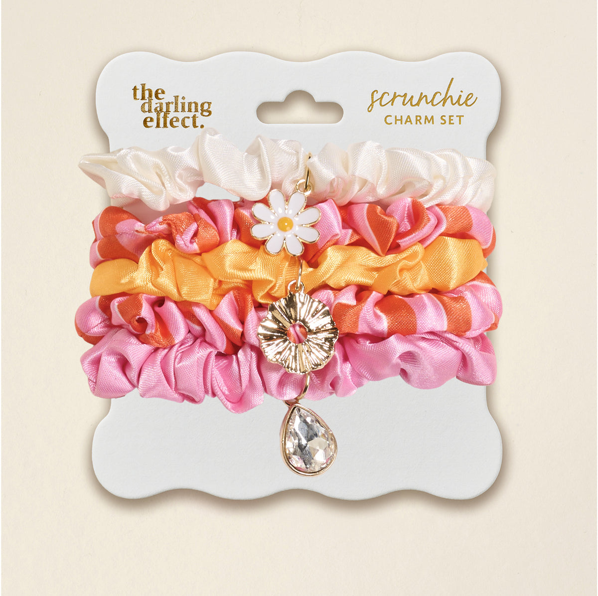 The Sicily Stripes Pink Scrunchie Charm Set by The Darling Effect features cream, pink, and orange stripes with a daisy charm and a teardrop gem for playful style.