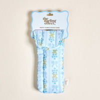 The Oh So Fancy Blue Puffy Sunglasses Case by The Darling Effect features a floral and ribbon pattern, magnetic flap closure, and comes packaged with a scalloped-edge label reading “the darling effect. PUFFY SUNGLASSES CASE.”.