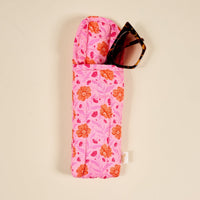 The Darling Effect’s Poppin' Petals Hot Pink Puffy Sunglasses Case features a bold orange and pink floral print, quilted design, and magnetic flap closure. Shown here with tortoiseshell sunglasses inside.