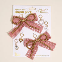 The Darling Effect’s Adore Me Dazzle Shoe Charm Pack includes two large pink lace bows with gold beads and six small sneaker charms—heart, teardrop gem, pearl cluster, flower, and a ring—perfect for accessorizing your shoes.