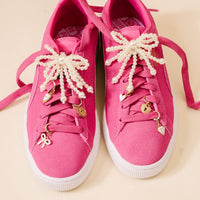 Add playful flair to your shoes with the-darling-effect’s Pretty in Pearl Dazzle Shoe Charm Pack—featuring gold and white bow, heart, flower & diamond charms plus pearl and bead lace decorations for bright pink sneakers.