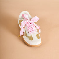 A white and beige sneaker with a gum sole is shown on a tan background, featuring The Darling Effect's Gingham Pink Step It Up Shoelaces laced in a wide, pink-and-white checkered bow.