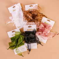 The Darling Effect’s Sheer White Step It Up Shoelaces are elegant organza laces, tied in bows and presented on white cardboard packaging.