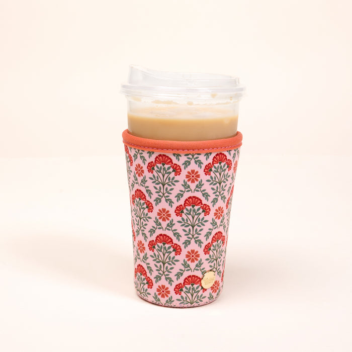 The Darling Effect's Large-Everbloom Dusty Rose Sip Savvy Drink Sleeve features a red floral pattern and orange trim, shown here holding a drink with a clear lid.