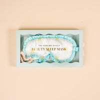 The Darling Effect Oh So Fancy Blue Beauty Sleep Mask gift box features a floral satin sleep mask with ruffled trim and two mini satin scrunchies in blue and nude shades.