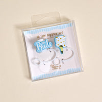 The Darling Effect's Blooming Bride Straw Topper Set includes two leak-resistant silicone toppers: a blue "Bride" with diamond and a white flower bouquet, both displayed on a chic blue and white striped background.