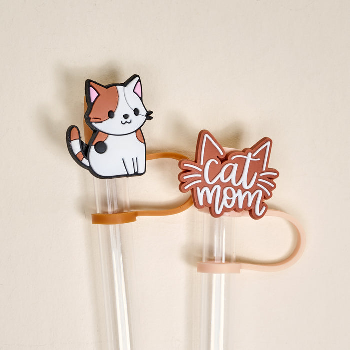 The Darling Effect's Cat Mom Straw Topper Set features two leak-resistant drinkware accessories: one with a cute calico cat, the other with a cat outline and playful "Cat Mom" text, shown on a light beige background.
