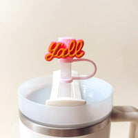 The Darling Effect's Classic Cowgirl Straw Topper Set features a pink and orange "y'all" charm on the straw of a white tumbler, bringing a playful pop to your drinkware accessories collection.