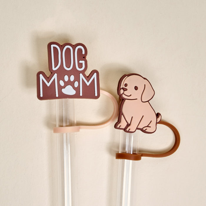 The Darling Effect Dog Mom Straw Topper Set includes two clear plastic straws with leak-resistant, colorful silicone toppers: one with "Dog Mom" and a paw print, the other with a cartoon light brown dog.