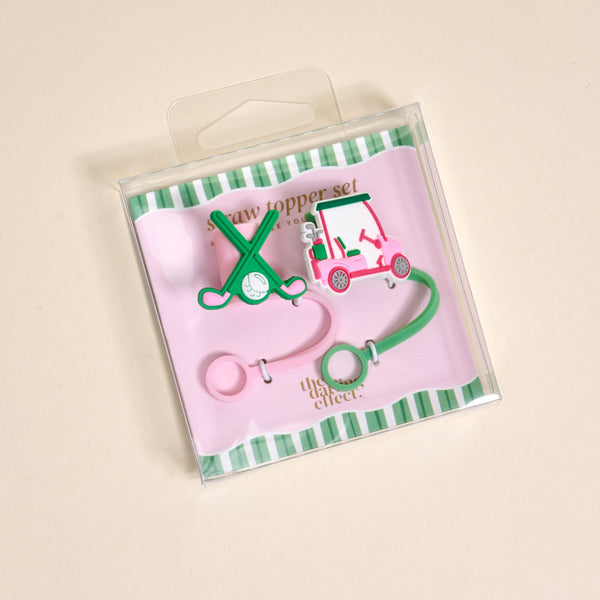 The Darling Effect Par-tee Pack Straw Topper Set includes two silicone toppers—one shaped like crossed golf clubs with a ball, the other a pink golf cart—on a pink and green striped card in a clear box.
