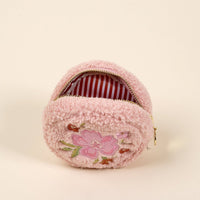 The Circle Dainty Floral Pink Teddy Pouch by the-darling-effect is a small, round, fluffy pink sherpa pouch with a zipper and embroidered flower on the front, plus red and white striped lining—perfect for your accessory set.