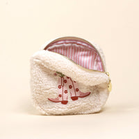 The Square Cowgirl Boots Teddy Pouch by the-darling-effect is a fluffy white sherpa pouch with a pink-striped lining and embroidered pink boots with flowers on the front, shown upright against a cream background.