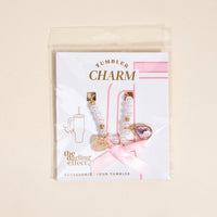 The Darling Effect Simply Coquette Tumbler Charm set features a strand of white beads with a pink bow, gold heart, and pink gem on a card labeled "Tumbler Charm"—a charming accessory for any drinkware charm lover.