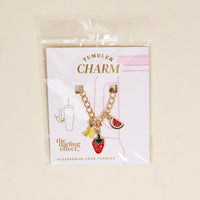 The Fruit Fusion Tumbler Charm by the-darling-effect includes a gold chain with banana, strawberry, and watermelon charms on a white "Tumbler Charm" card—fun accessories to brighten up your drinkware.