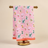 The Darling Effect’s “It’s Mahj Time” Waffle Tea Towel, a pink and absorbent kitchen towel, hangs neatly on a gold stand against a beige background.