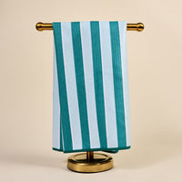 The Darling Effect's Sicily Stripes Teal Waffle Tea Towel hangs neatly on a gold towel stand against a plain beige background.