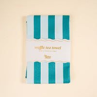 The Sicily Stripes Teal Waffle Tea Towel by The Darling Effect measures 18x25" and features teal and light blue stripes—an absorbent, stylish addition to any kitchen.